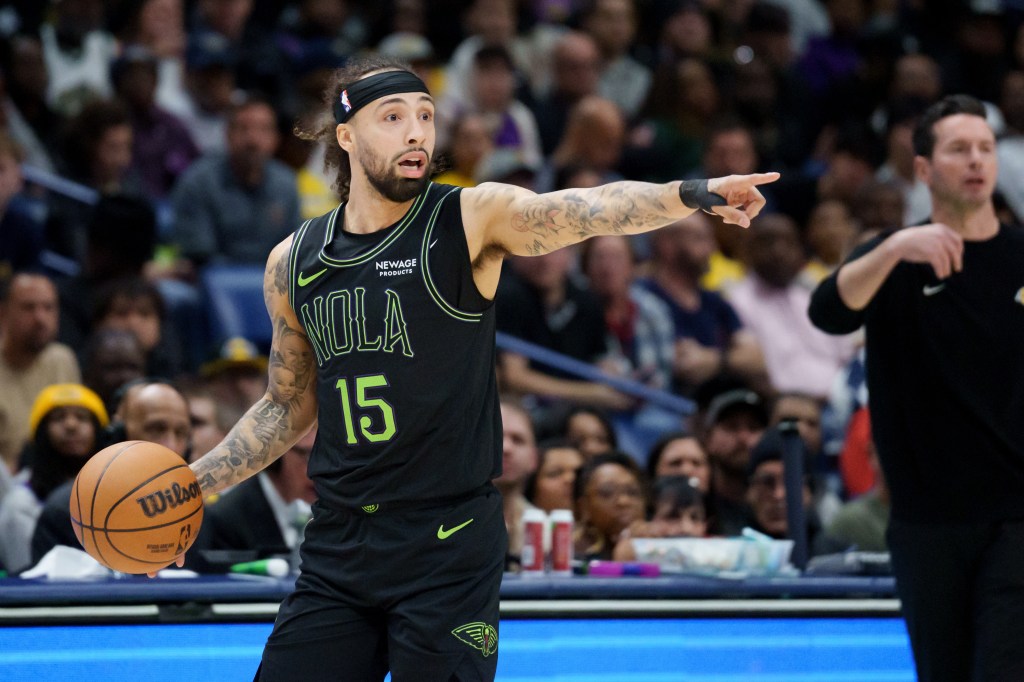 New Orleans Pelicans guard Jose Alvarado (15) points while holding a basketball next to Los Angeles Lakers Head Coach JJ Redick.