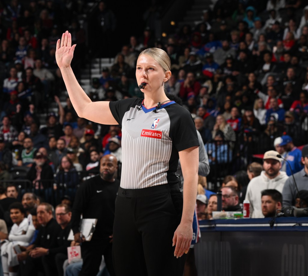 Referee Jenna Reneau raising her arm during a Celtics vs 76ers basketball game.