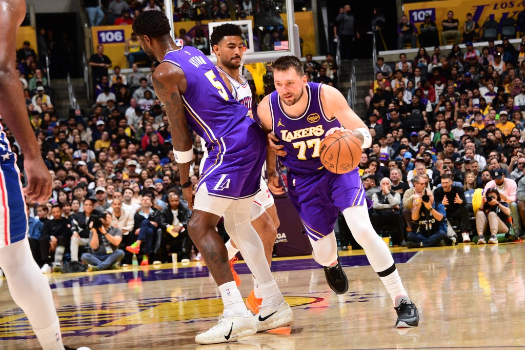 Luka Doncic (number 77) of the Los Angeles Lakers drives to the basket while being defended by a Philadelphia 76ers player.