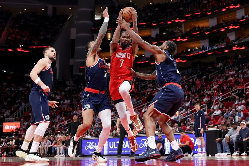 Kevin Durant #7 of the Houston Rockets goes to the basket against John Collins #20 and Kawhi Leonard #2 of the Los Angeles Clippers .