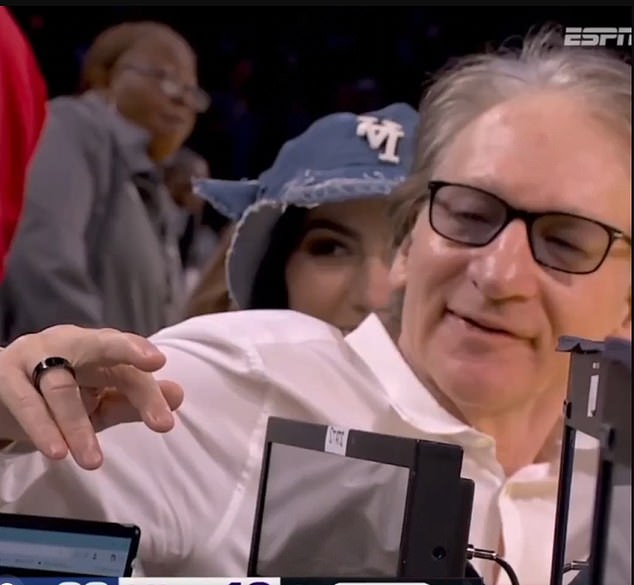 Political commentator Bill Maher shows off his injured finger after a collision at an NBA game
