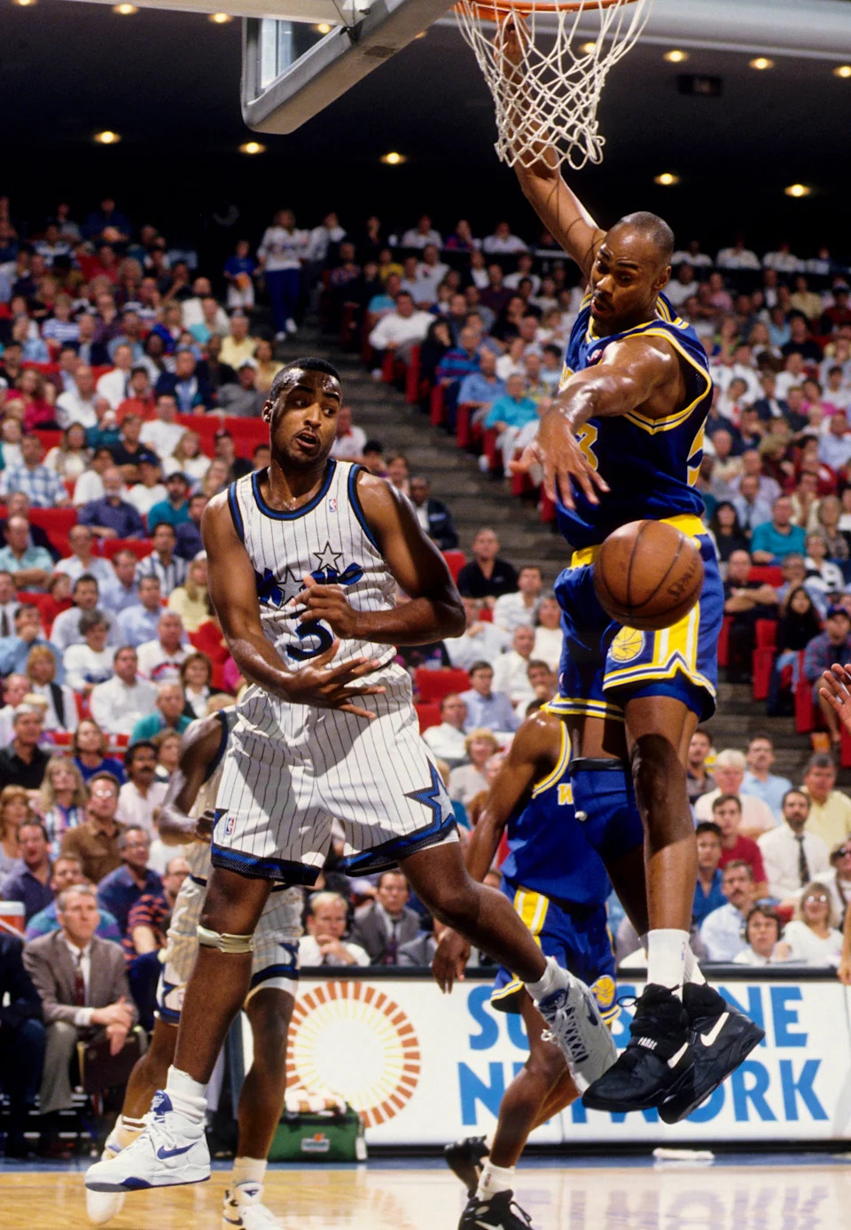 Nov 19, 1992; Orlando, FL, USA; FILE PHOTO; Orlando Magic guard Dennis Scott passes the ball around Golden State Warriors center Alton Lister (53) at the Orlando Arena. Mandatory Credit: USA TODAY Sports