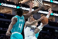 Dallas Mavericks forward P.J. Washington drives to the basket between Charlotte Hornets...