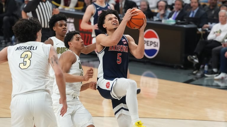Arizona guard Brayden Burries, right, drives to the rim past...