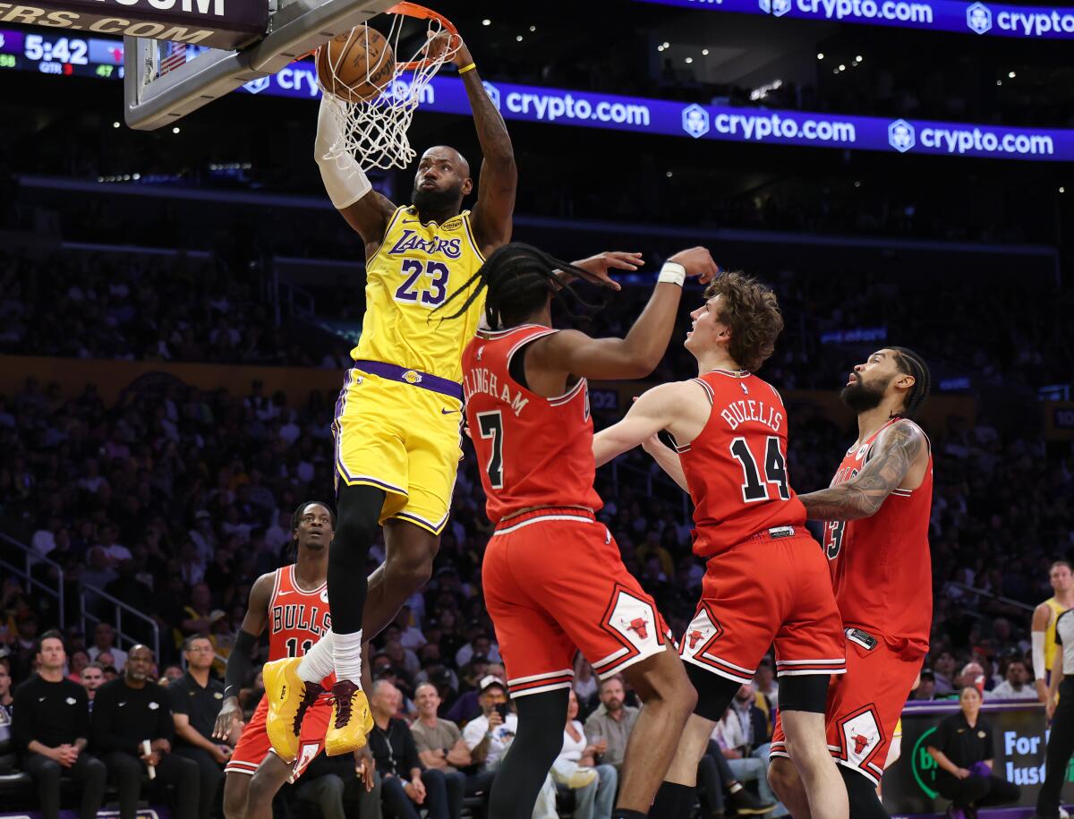 Lakers forward LeBron James, top, hangs onto the rim as he dunks the ball over three Bulls defenders.
