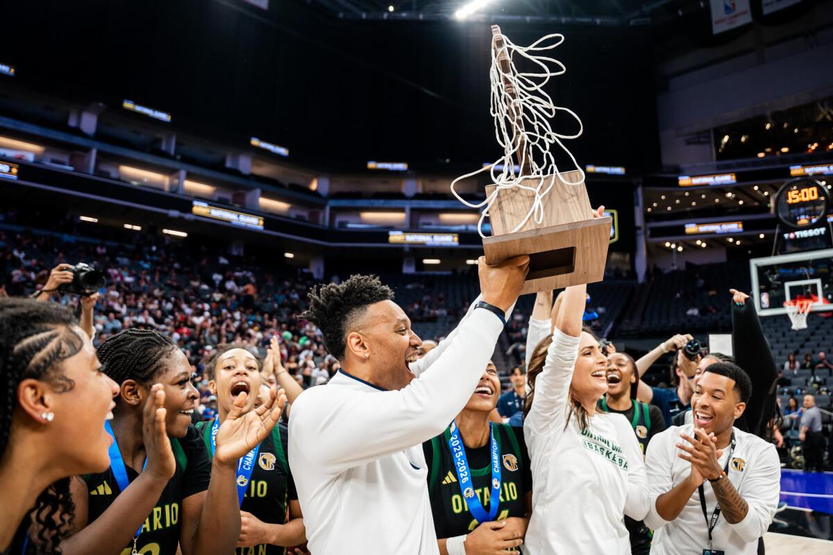 Ontario Christian coach Aundre Cummings (left) hoists the Open Division girls state championship trophy.