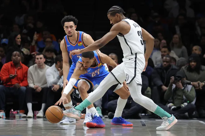 Mar 18, 2026; Brooklyn, New York, USA; Brooklyn Nets guard Ochai Agbaji (30) kicks the ball against Oklahoma City Thunder guards Aaron Wiggins (21) and Jared McCain (3) during the first quarter at Barclays Center. Mandatory Credit: Brad Penner-Imagn Images
