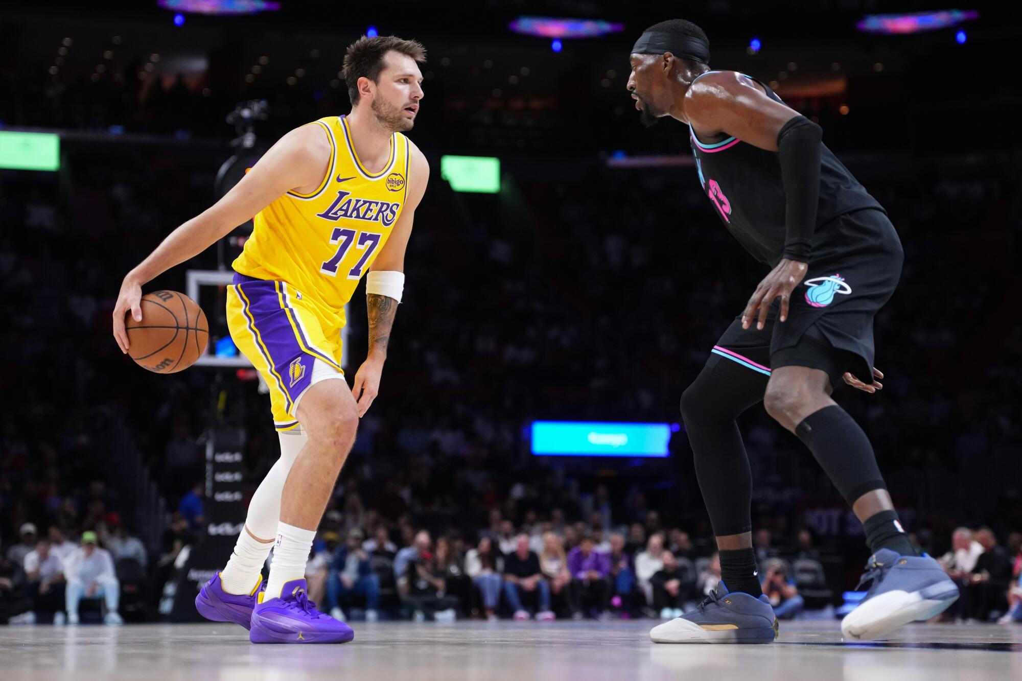 Lakers star Luka Doncic, left, controls the ball in front of Miami's Bam Adebayo during the first quarter Thursday.