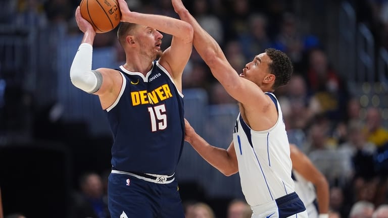Denver Nuggets center Nikola Jokić, left, looks to pass the...