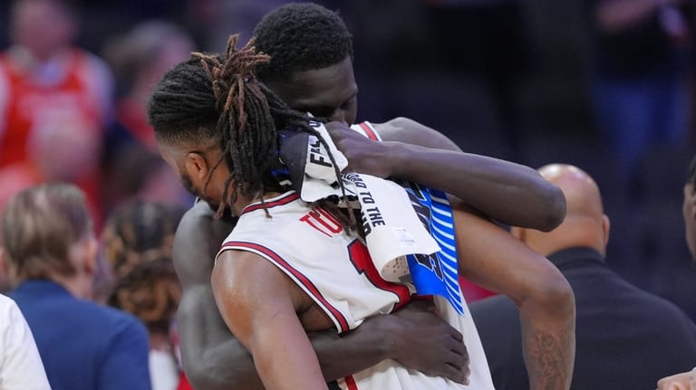 Houston forward Joseph Tugler (11) is embraced by a teammate...