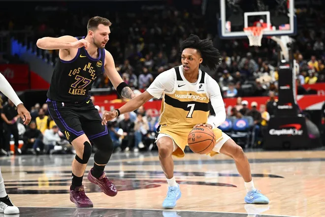Jan 30, 2026; Washington, District of Columbia, USA; Washington Wizards guard Bub Carrington (7) dribbles as Los Angeles Lakers forward/guard Luka Dončić (77) defends during the first half at Capital One Arena.