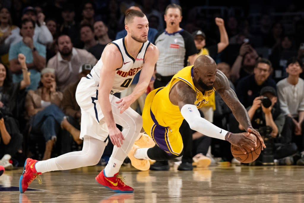 Los Angeles Lakers forward LeBron James, right, dives for the loose ball past Denver Nuggets guard Christian Braun during the second half of an NBA basketball game in Los Angeles, Saturday, March 14, 2026. (AP Photo/Kyusung Gong) AP