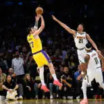 Mar 14, 2026; Los Angeles, California, USA; Los Angeles Lakers guard Luka Doncic (77) shoots a game winning shot while under pressure from Denver Nuggets forward Spencer Jones (21) during overtime at Crypto.com Arena. Mandatory Credit: William Liang-Imagn Images