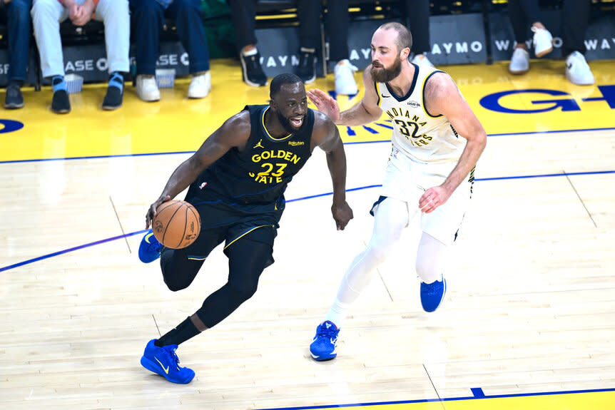 Draymond Green dribbles a basketball against Indiana Pacers on a basketball court during a game.