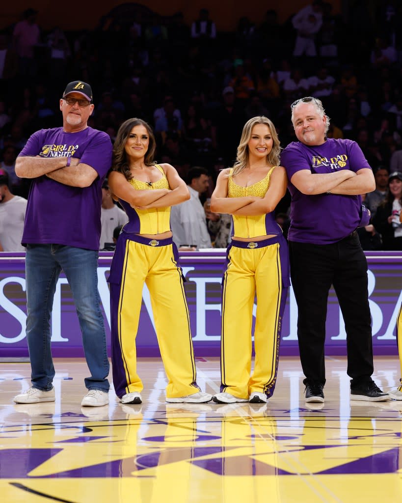 Two men and two Laker Girls stand on a basketball court.