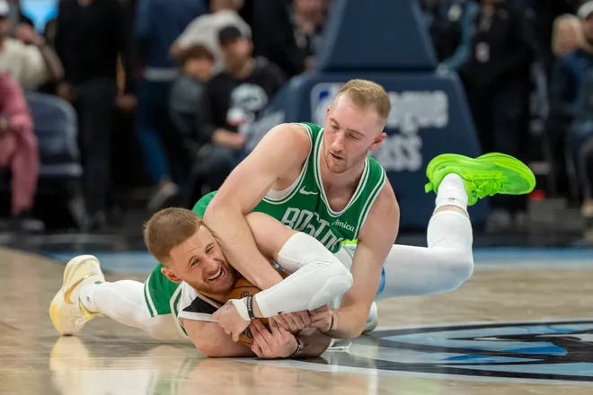 Jan 2, 2025; Minneapolis, Minnesota, USA; Boston Celtics forward Sam Hauser (30) and Minnesota Timberwolves guard Donte DiVincenzo (0) dive for a loose ball in the second half at Target Center. Mandatory Credit: Jesse Johnson-Imagn Images