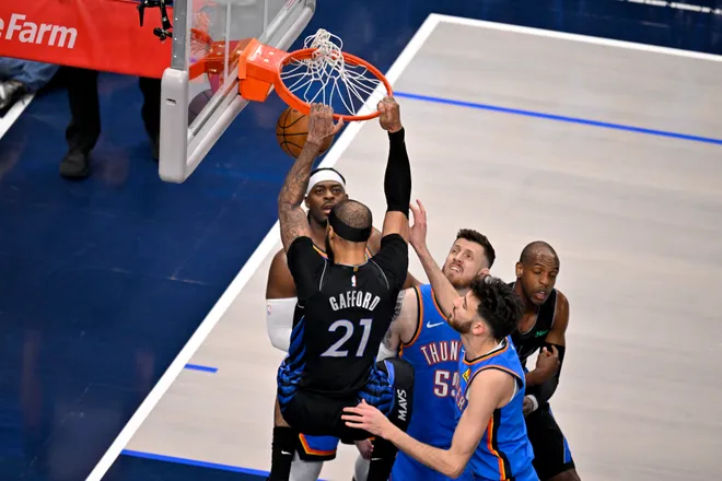 Mar 1, 2026; Dallas, Texas, USA; Dallas Mavericks forward Daniel Gafford (21) dunks the ball as Oklahoma City Thunder guard Shai Gilgeous-Alexander (2) and center Isaiah Hartenstein (55) and center Chet Holmgren (7) look on during the first quarter at the American Airlines Center. Mandatory Credit: Jerome Miron-Imagn Images