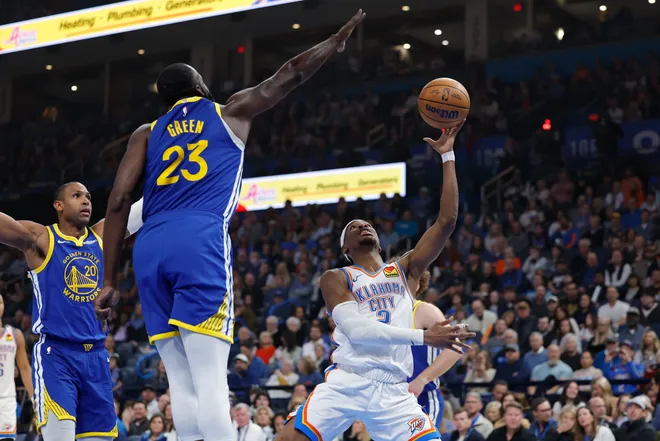 Mar 7, 2026; Oklahoma City, Oklahoma, USA; Oklahoma City Thunder guard Shai Gilgeous-Alexander (2) shoots as Golden State Warriors forward Draymond Green (23) defends during the first half at Paycom Center. Mandatory Credit: Alonzo Adams-Imagn Images
