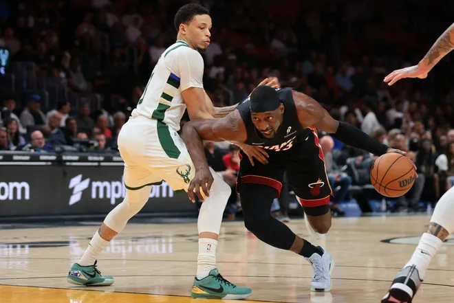 Mar 12, 2026; Miami, Florida, USA; Miami Heat center Bam Adebayo (13) drives to the basket against Milwaukee Bucks guard Ryan Rollins (13) during the third quarter at Kaseya Center.