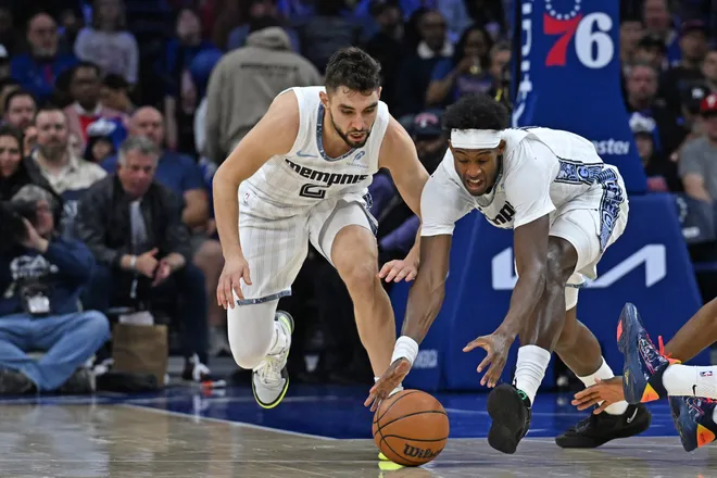 Mar 10, 2026; Philadelphia, Pennsylvania, USA; Memphis Grizzlies guard Ty Jerome (2) and forward Olivier-Maxence Prosper (18) reach for loose ball against the Philadelphia 76ers during the first half at Xfinity Mobile Arena. Mandatory Credit: Eric Hartline-Imagn Images