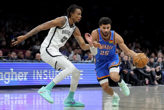 Mar 18, 2026; Brooklyn, New York, USA; Oklahoma City Thunder guard Ajay Mitchell (25) drives to the basket against Brooklyn Nets center Nic Claxton (33) during the second quarter at Barclays Center. Mandatory Credit: Brad Penner-Imagn Images