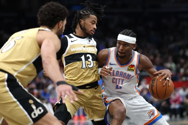 WASHINGTON, DC - MARCH 21: Shai Gilgeous-Alexander #2 of the Oklahoma City Thunder dribbles past Sharife Cooper #13 of the Washington Wizards during the first half at Capital One Arena on March 21, 2026 in Washington, DC. NOTE TO USER: User expressly acknowledges and agrees that, by downloading and or using this photograph, User is consenting to the terms and conditions of the Getty Images License Agreement. (Photo by Patrick Smith/Getty Images)