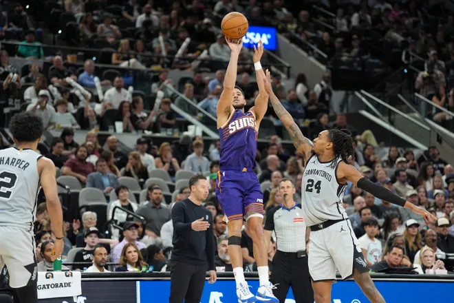 Mar 19, 2026; San Antonio, Texas, USA; Phoenix Suns guard Devin Booker (1) shoots in front of San Antonio Spurs guard Devin Vassell (24) in the second half at Frost Bank Center. Mandatory Credit: Daniel Dunn-Imagn Images