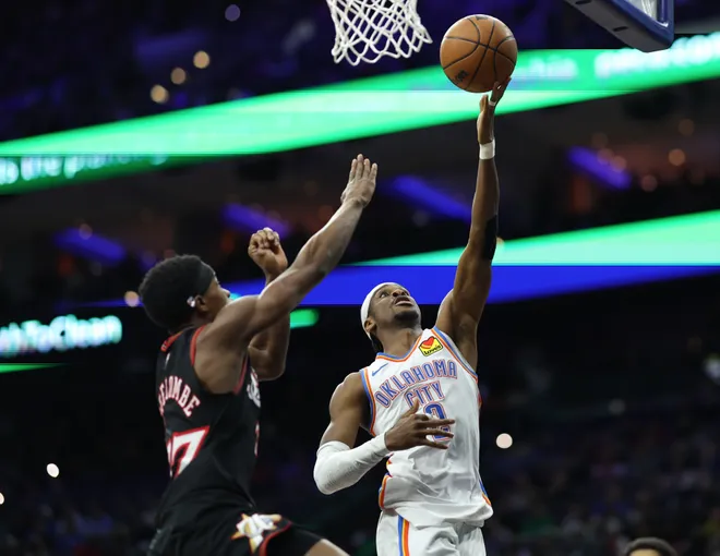 Mar 23, 2026; Philadelphia, Pennsylvania, USA; Oklahoma City Thunder guard Shai Gilgeous-Alexander (2) scores past Philadelphia 76ers guard Vj Edgecombe (77) during the third quarter at Xfinity Mobile Arena. Mandatory Credit: Bill Streicher-Imagn Images