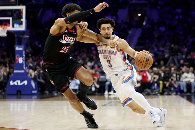 PHILADELPHIA, PENNSYLVANIA - MARCH 23: Jared McCain #3 of the Oklahoma City Thunder drives past Dominick Barlow #25 of the Philadelphia 76ers during the first half at Xfinity Mobile Arena on March 23, 2026 in Philadelphia, Pennsylvania. NOTE TO USER: User expressly acknowledges and agrees that, by downloading and or using this photograph, User is consenting to the terms and conditions of the Getty Images License Agreement. (Photo by Emilee Chinn/Getty Images)