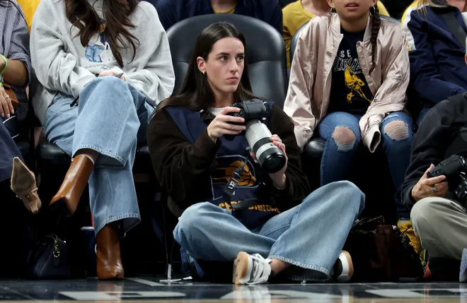INDIANAPOLIS, INDIANA - MARCH 25: Caitlin Clark of the Indiana Fever sits on the baseline and makes photographs during the Indiana Pacers game against the Los Angeles Lakers at Gainbridge Fieldhouse on March 25, 2026, in Indianapolis, Indiana. NOTE TO USER: User expressly acknowledges and agrees that, by downloading and or using this photograph, User is consenting to the terms and conditions of the Getty Images License Agreement (Photo by Andy Lyons/Getty Images)
