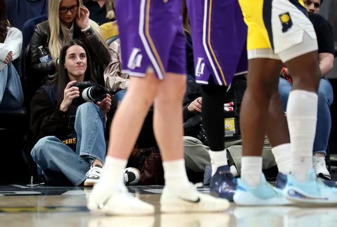 INDIANAPOLIS, INDIANA - MARCH 25: Caitlin Clark of the Indiana Fever sits on the baseline and makes photographs during the Indiana Pacers game against the Los Angeles Lakers at Gainbridge Fieldhouse on March 25, 2026, in Indianapolis, Indiana. NOTE TO USER: User expressly acknowledges and agrees that, by downloading and or using this photograph, User is consenting to the terms and conditions of the Getty Images License Agreement (Photo by Andy Lyons/Getty Images)