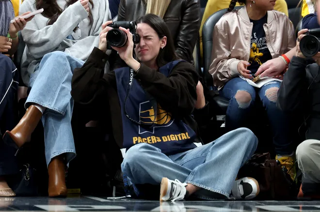 INDIANAPOLIS, INDIANA - MARCH 25: Caitlin Clark of the Indiana Fever sits on the baseline and makes photographs during the Indiana Pacers game against the Los Angeles Lakers at Gainbridge Fieldhouse on March 25, 2026, in Indianapolis, Indiana. NOTE TO USER: User expressly acknowledges and agrees that, by downloading and or using this photograph, User is consenting to the terms and conditions of the Getty Images License Agreement (Photo by Andy Lyons/Getty Images)