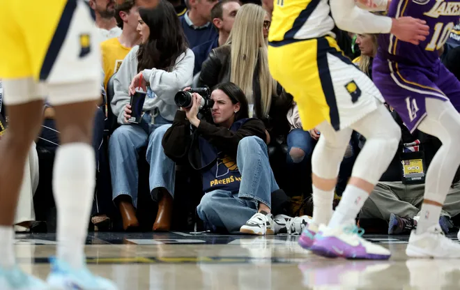 INDIANAPOLIS, INDIANA - MARCH 25: Caitlin Clark of the Indiana Fever sits on the baseline and makes photographs during the Indiana Pacers game against the Los Angeles Lakers at Gainbridge Fieldhouse on March 25, 2026, in Indianapolis, Indiana. NOTE TO USER: User expressly acknowledges and agrees that, by downloading and or using this photograph, User is consenting to the terms and conditions of the Getty Images License Agreement (Photo by Andy Lyons/Getty Images)