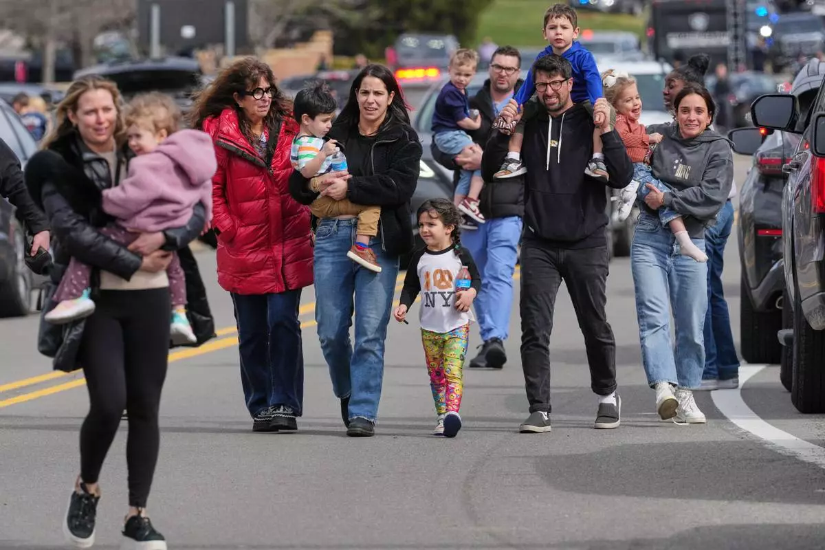 Law enforcement escort families with children away from the Temple Israel synagogue Thursday, March 12, 2026, in West Bloomfield Township, Mich. (AP Photo/Paul Sancya)
