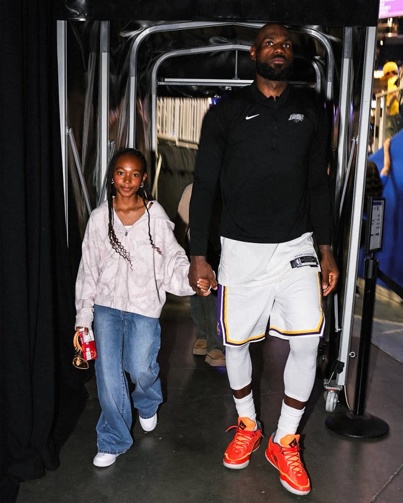 LeBron James holding hands with his daughter Zhuri, both looking forward.