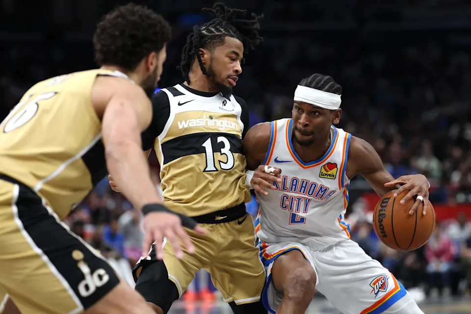 WASHINGTON, DC - MARCH 21: Shai Gilgeous-Alexander #2 of the Oklahoma City Thunder dribbles past Sharife Cooper #13 of the Washington Wizards during the first half at Capital One Arena on March 21, 2026 in Washington, DC. NOTE TO USER: User expressly acknowledges and agrees that, by downloading and or using this photograph, User is consenting to the terms and conditions of the Getty Images License Agreement. (Photo by Patrick Smith/Getty Images)