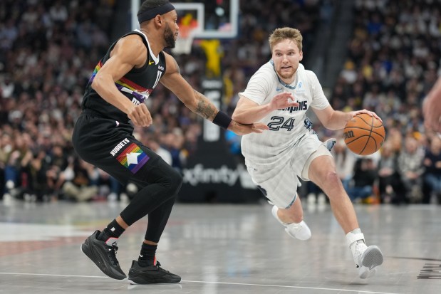 Memphis Grizzlies guard Cam Spencer (24) drives past Denver Nuggets guard Bruce Brown (11) in the first half of an NBA basketball game Wednesday, Feb. 11, 2026, in Denver. (AP Photo/David Zalubowski)