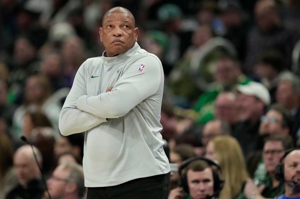 Doc Rivers standing courtside with his arms crossed.