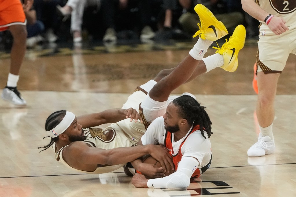 Golden State Warriors guard Moses Moody reaching for the ball while falling over Los Angeles Clippers guard Darius Garland.