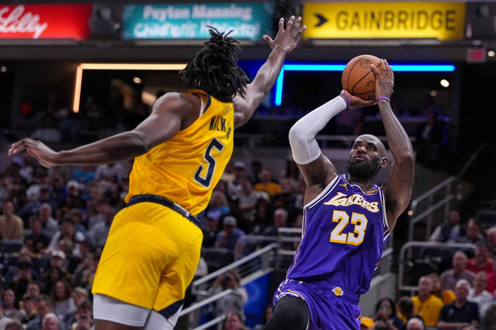 LeBron James in a purple Lakers jersey shoots a basketball while Jarace Walker in a yellow Pacers jersey defends.