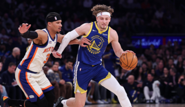 A Golden State Warriors player dribbles the basketball while being closely guarded by a New York Knicks player during a game.