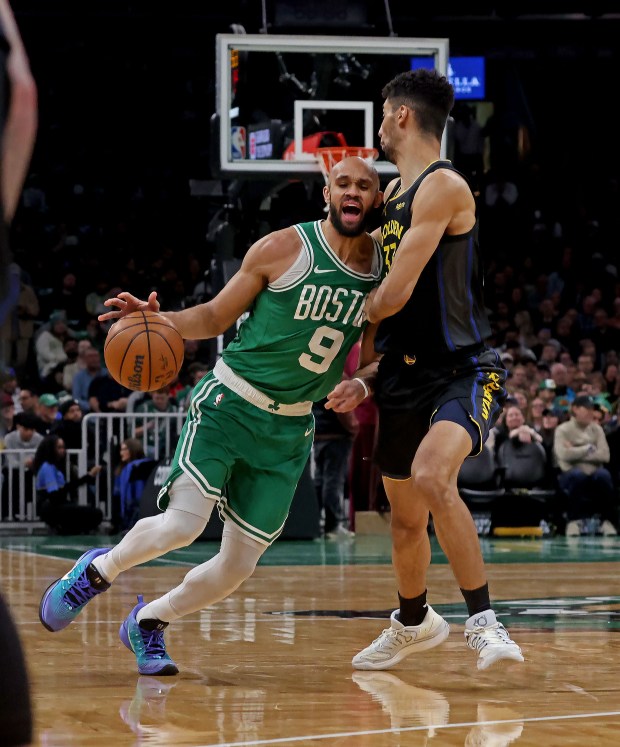 Boston Celtics guard Derrick White, left, drives into Golden State Warriors forward Malevy Leons as the Celtics take on the Warriors at the TD Garden. (Staff photo by Stuart Cahill)
