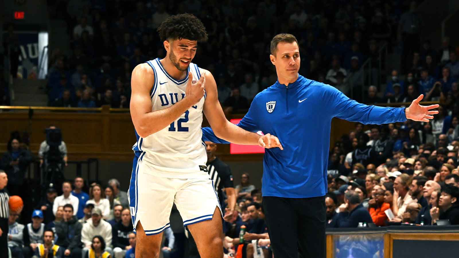 Duke Blue Devils head coach Jon Scheyer (right) directs forward Cameron Boozer (12) to the bench after being poked in the eye during the first half against the Virginia Cavaliers at Cameron Indoor Stadium.