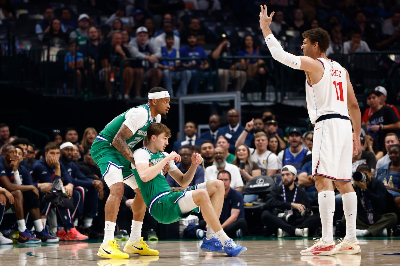 Dallas Mavericks forward Daniel Gafford (21) helps forward Cooper Flagg (32) off the court...
