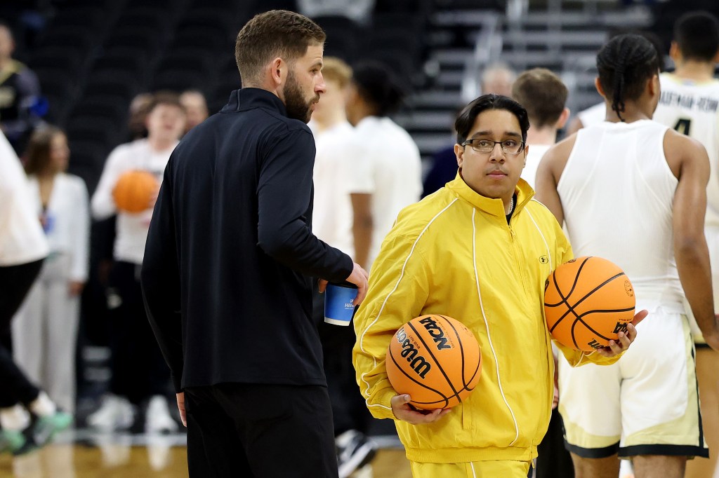 Two coaches and a basketball player on a court.
