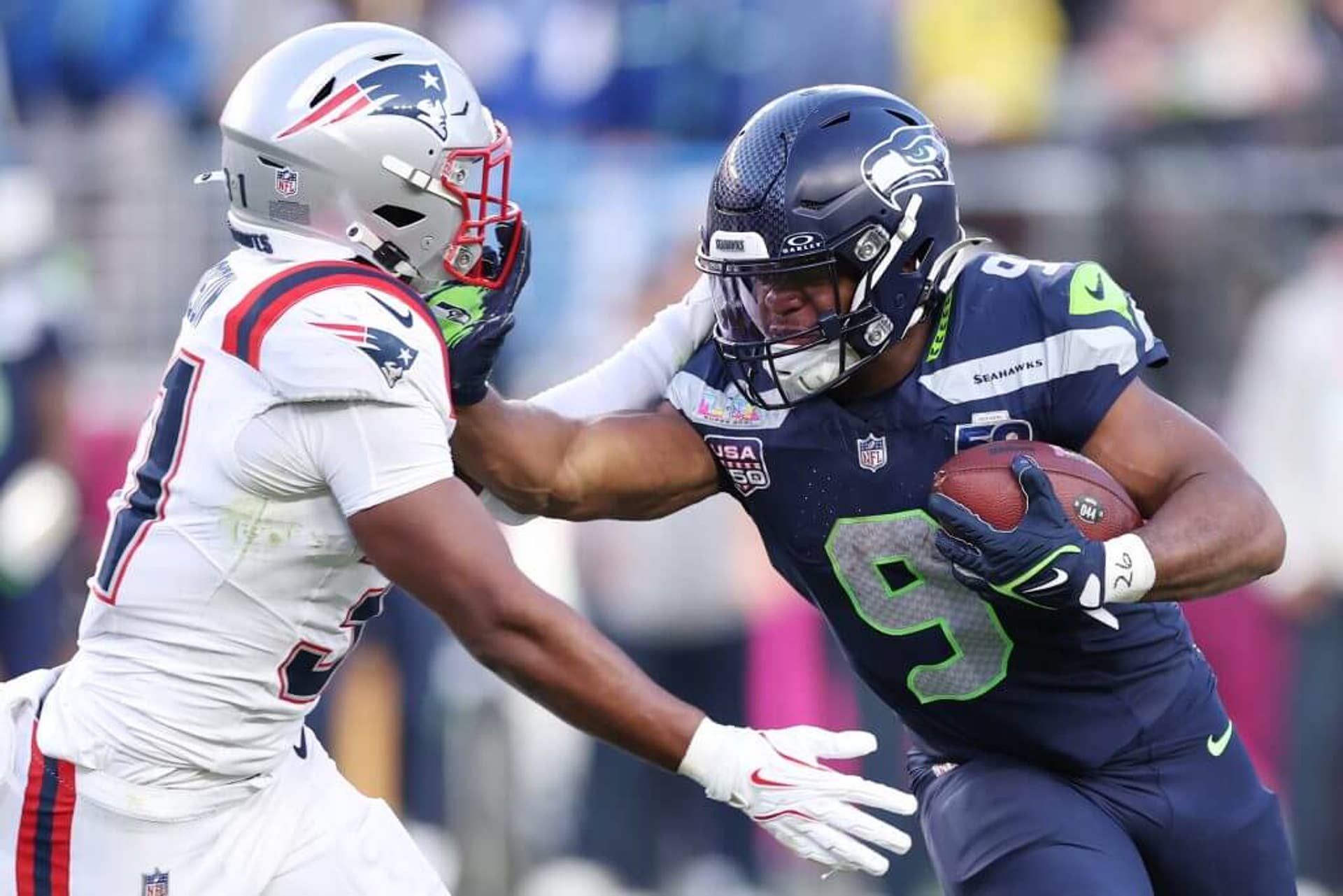Kenneth Walker III #9 of the Seattle Seahawks runs against Craig Woodson #31 of the New England Patriots during the second quarter in Super Bowl LX.