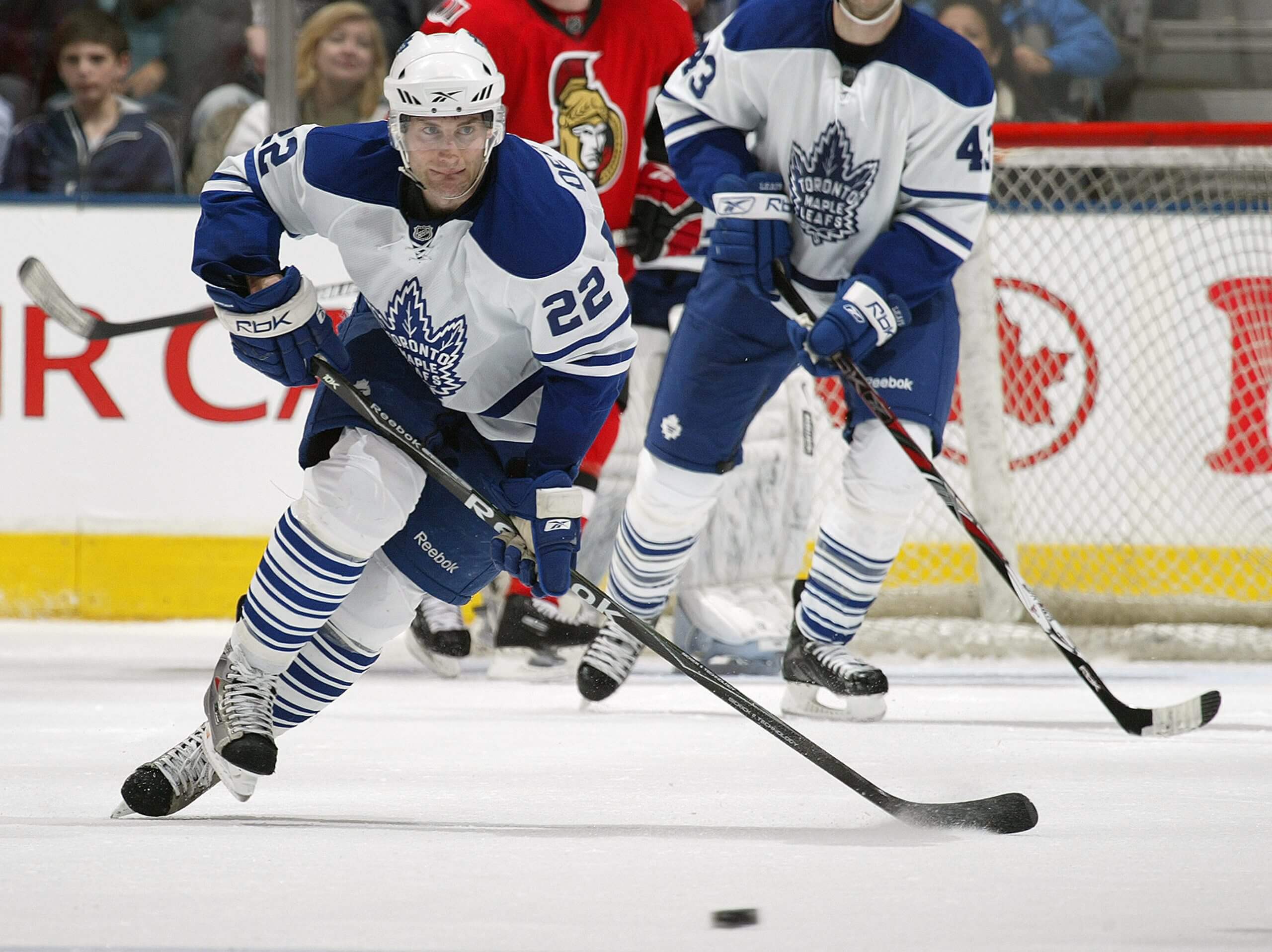 Boyd Devereaux skates with the puck during a Leafs game, with another Leaf and the Ottawa Senators goalie behind him.