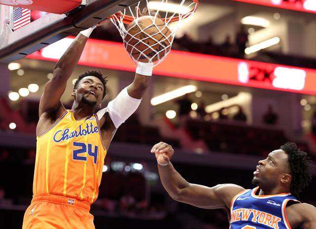 Charlotte Hornets guard Brandon Miller throws down a two-handed dunk off a missed shot by teammate Kon Knueppel during action against the New York Knicks at Spectrum Center in Charlotte, North Carolina, on Thursday, March 26, 2026. At right is Knicks forward/guard OG Anunoby.