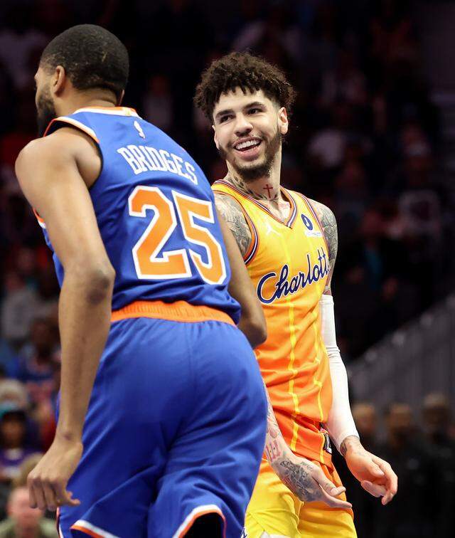 Charlotte Hornets guard LaMelo Ball, right, smiles after hitting a three-point shot over New York Knicks guard/forward Mikal Bridges, left, during action at Spectrum Center in Charlotte, North Carolina, on Thursday, March 26, 2026. 