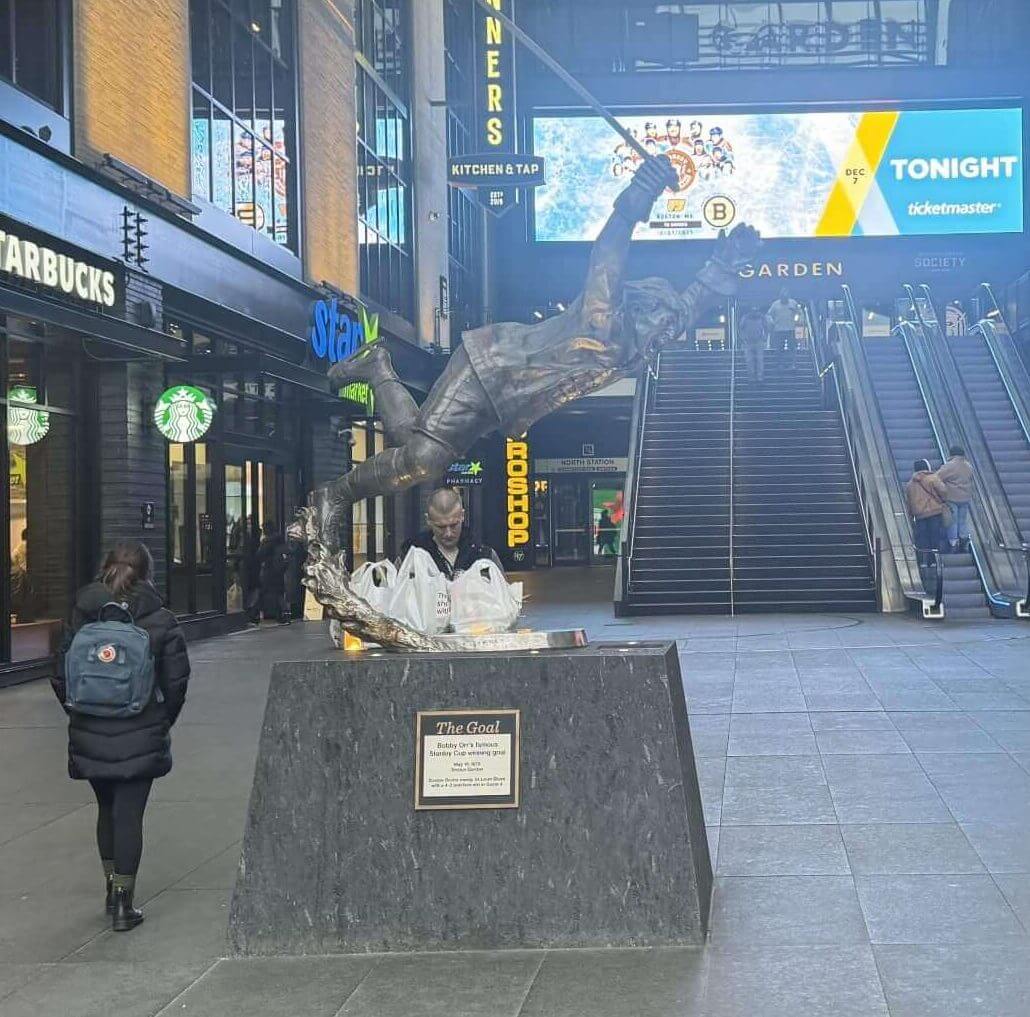 A statue of Bobby Orr, which shows him in midair after putting the puck past Glenn Hall to win the 1970 Stanley Cup Final, sits in front of The Hub on Causeway. (Steve Buckley / The Athletic)
